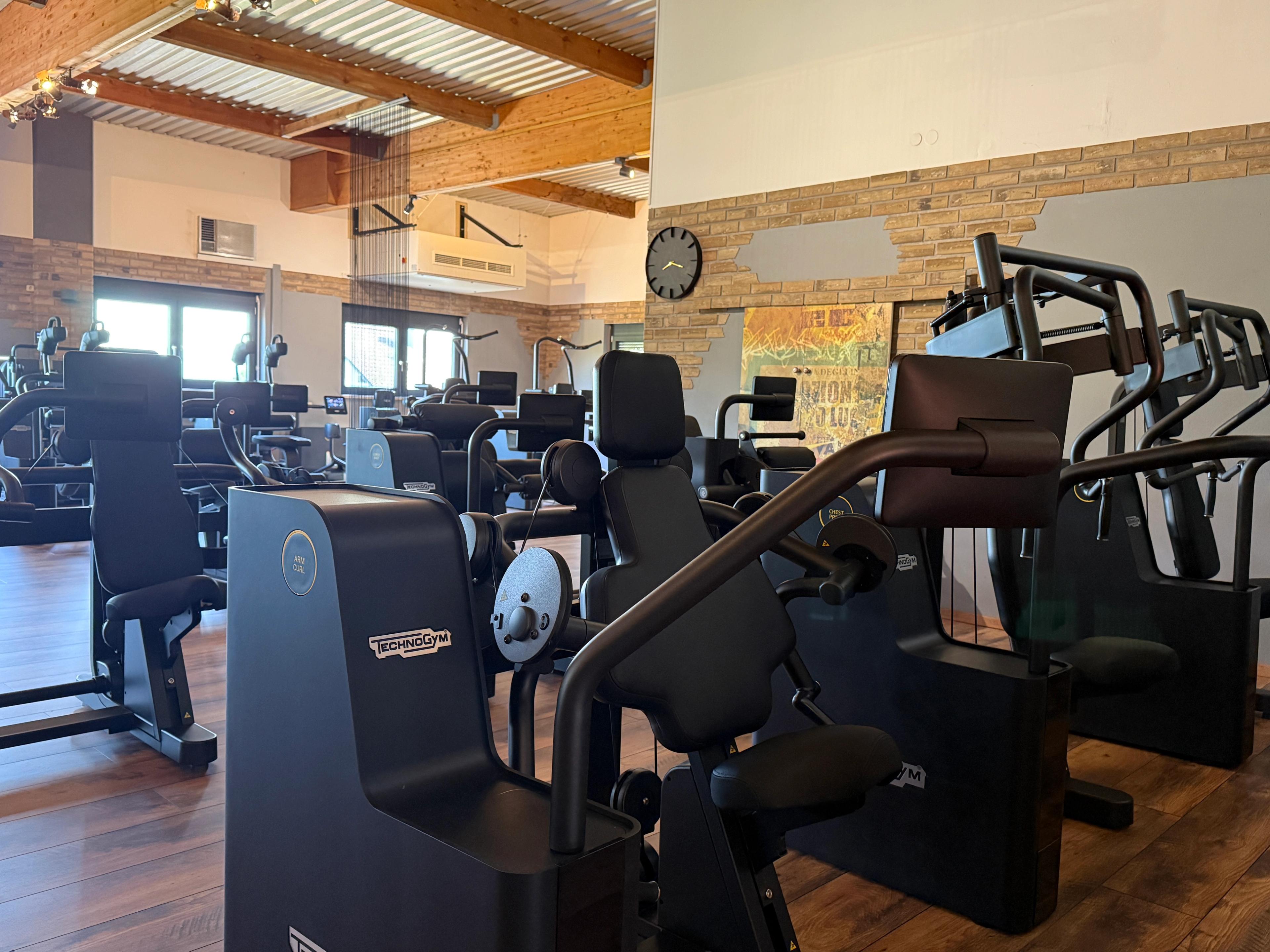 Moderne Fitnessgeräte in einem stilvoll eingerichteten Fitnessstudio mit Holzboden und dekorativen Wänden