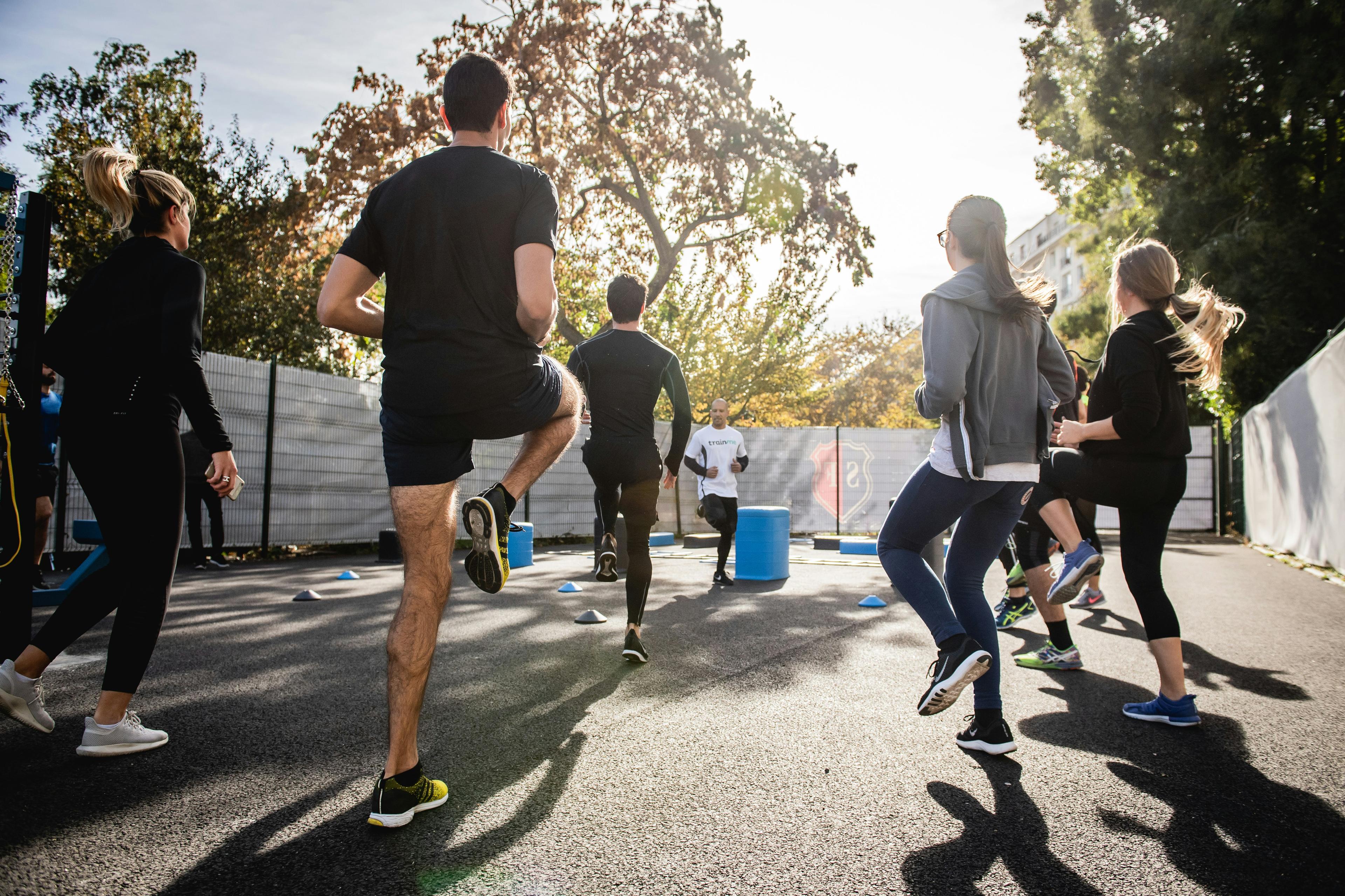 Menschen in sportlicher Kleidung beim Outdoor-Fitness-Training auf einem sonnigen Platz