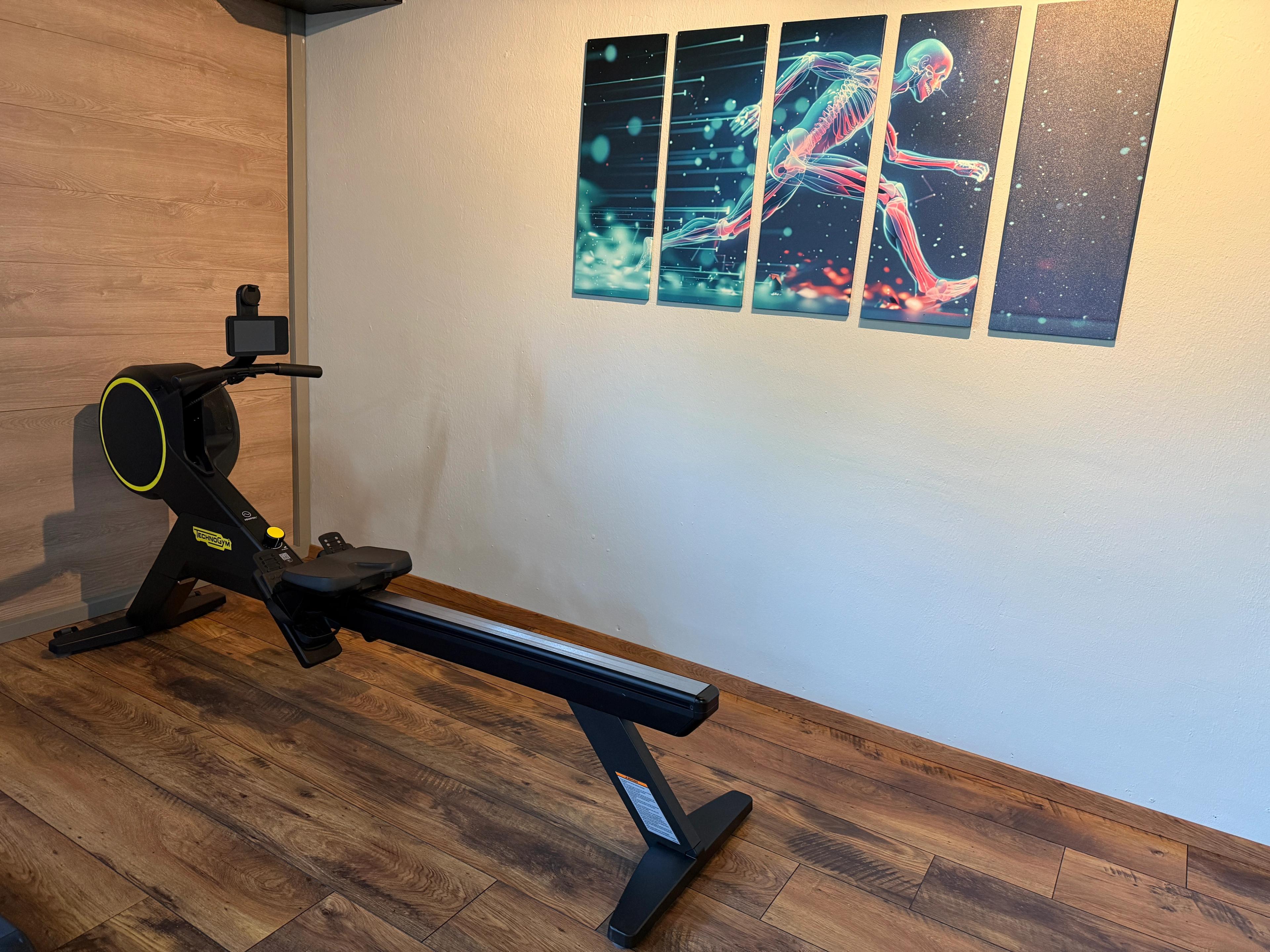 Ein modernes Rudergerät in einem Trainingsraum mit einem Wandbild, das einen laufenden Menschen zeigt