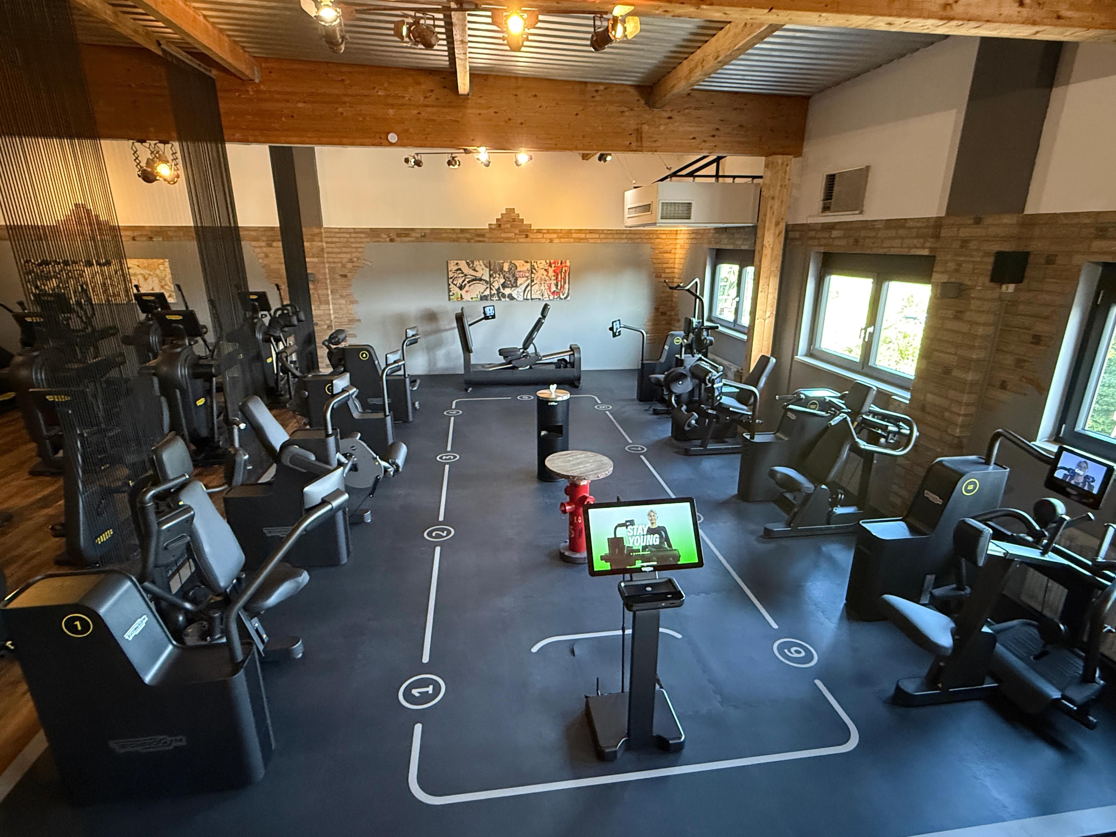 Mehrere Personen trainieren an modernen Fitnessgeräten in einem digital unterstützten Gruppentraining