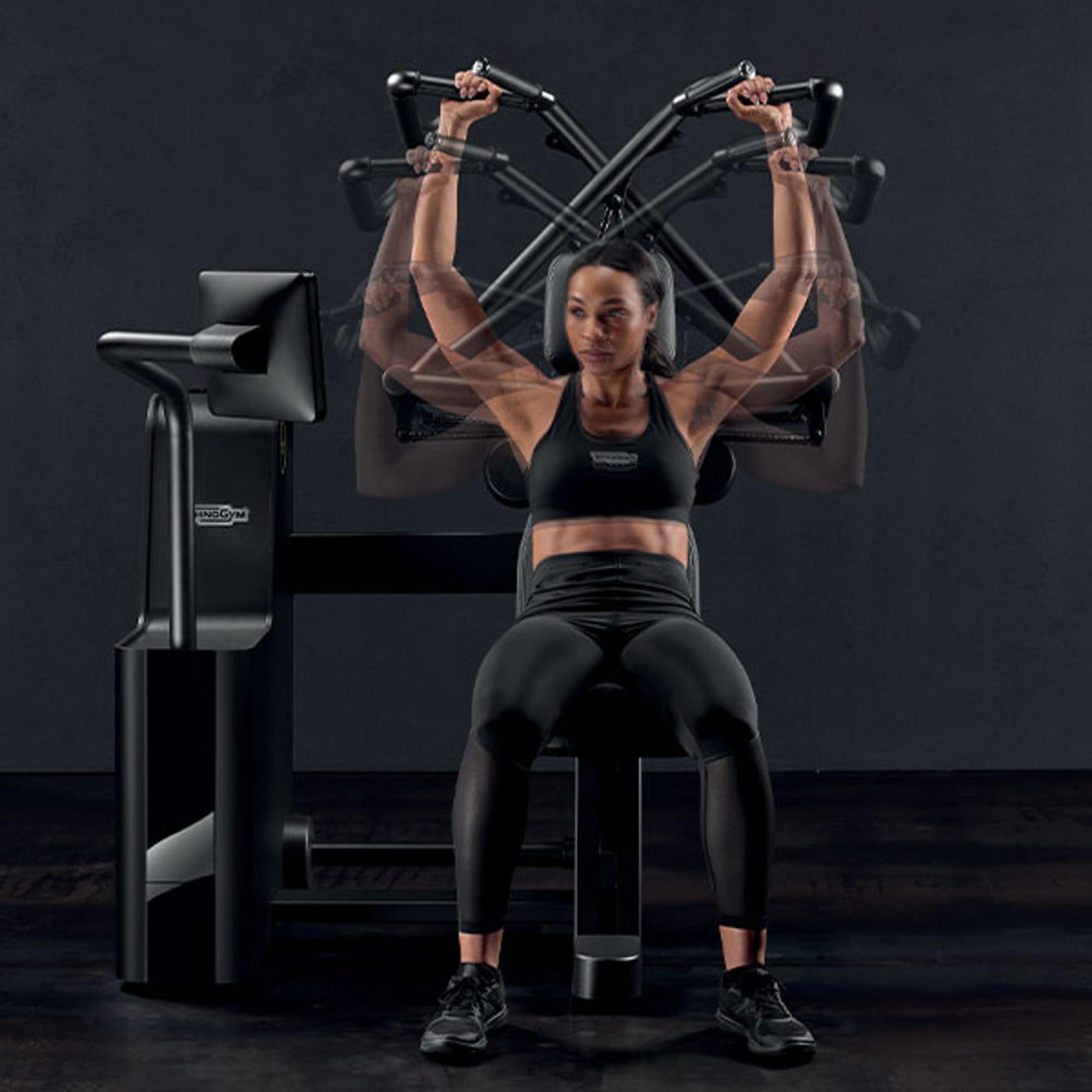 Eine Frau in Sportkleidung trainiert an einem modernen Fitnessgerät im Fitnessstudio