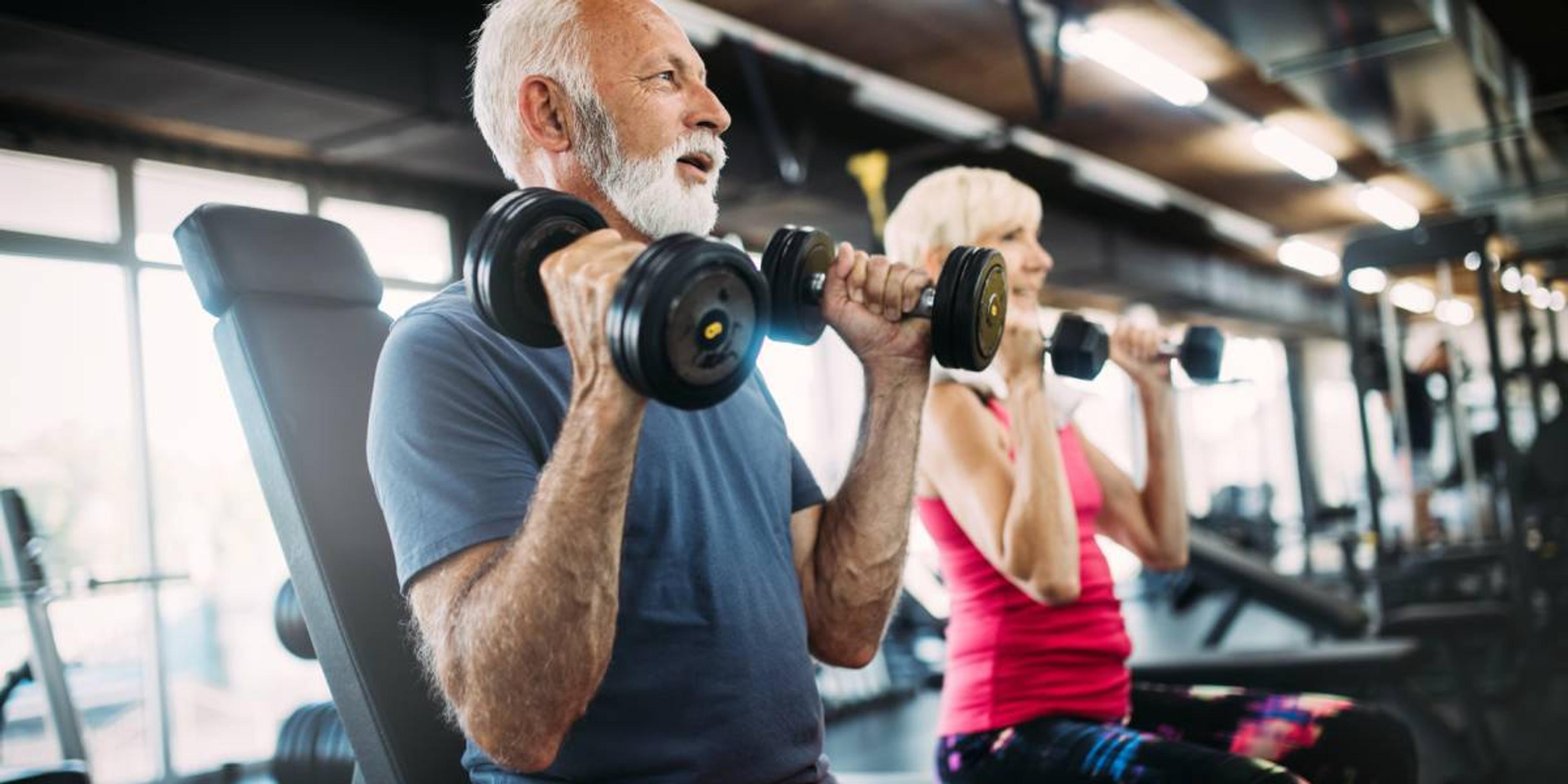 Älterer Mann und ältere Frau trainieren mit Hanteln in einem Fitnessstudio