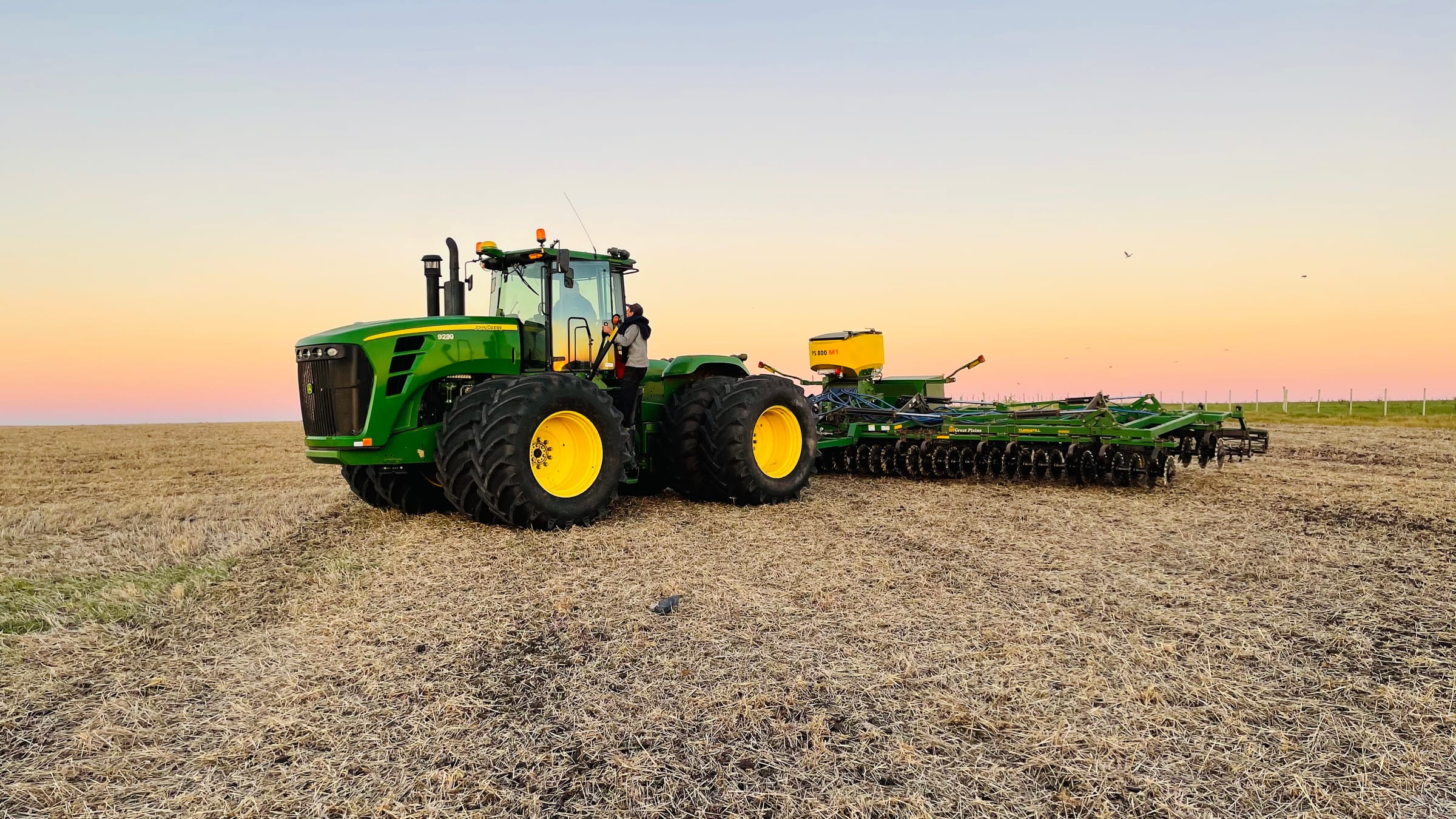 Tractor articulado con sembradora neumática al atardecer