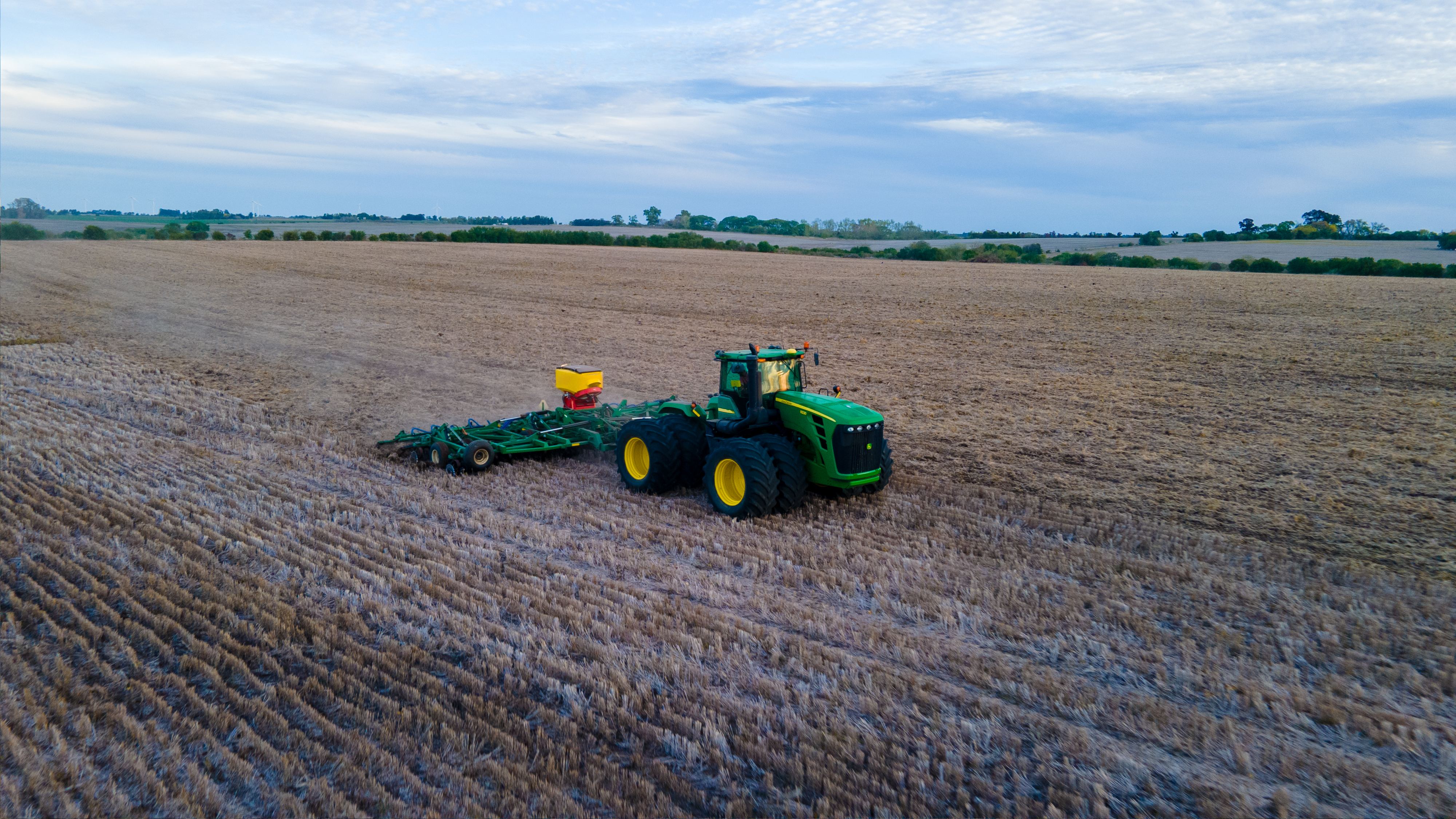 Tractor con equipo de siembra en un lote grande de rastrojo, vista aérea
