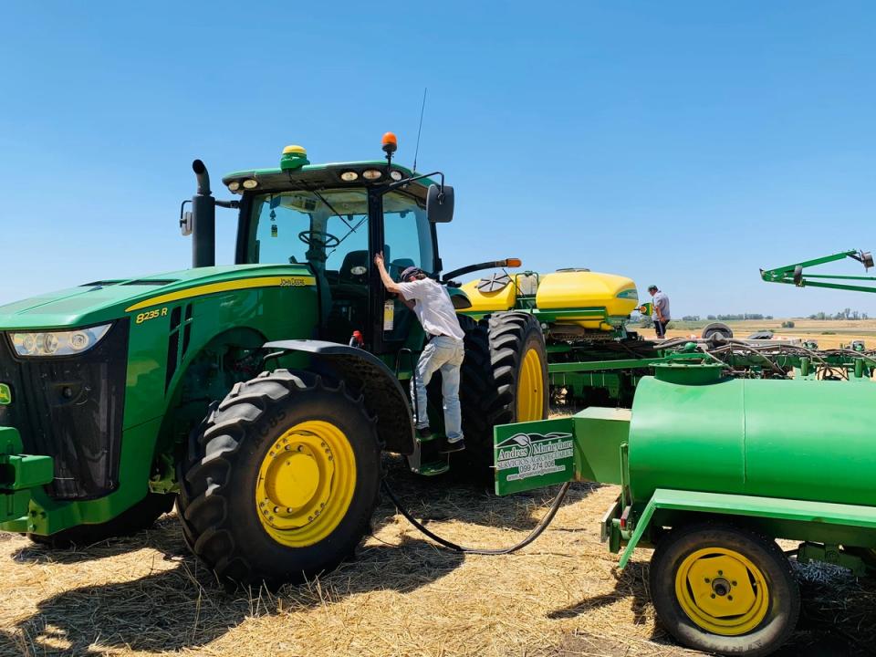 Operario subiendo a la cabina del tractor, con el carro tanque al lado