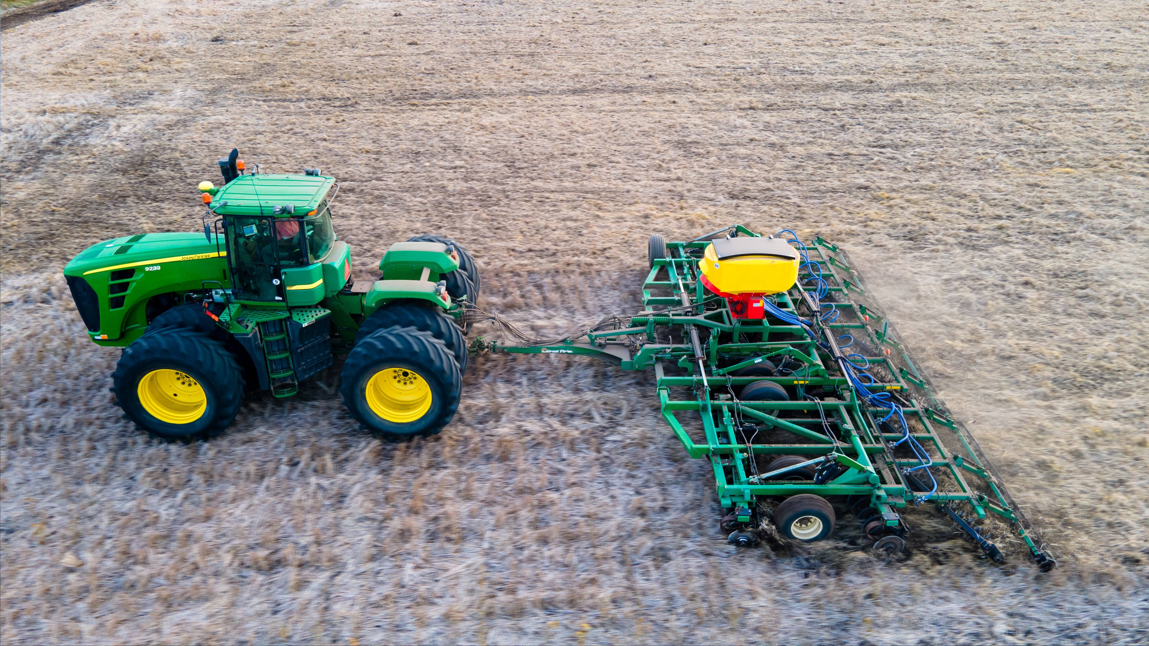Tractor con cultivador de campo sobre el rastrojo, vista aérea