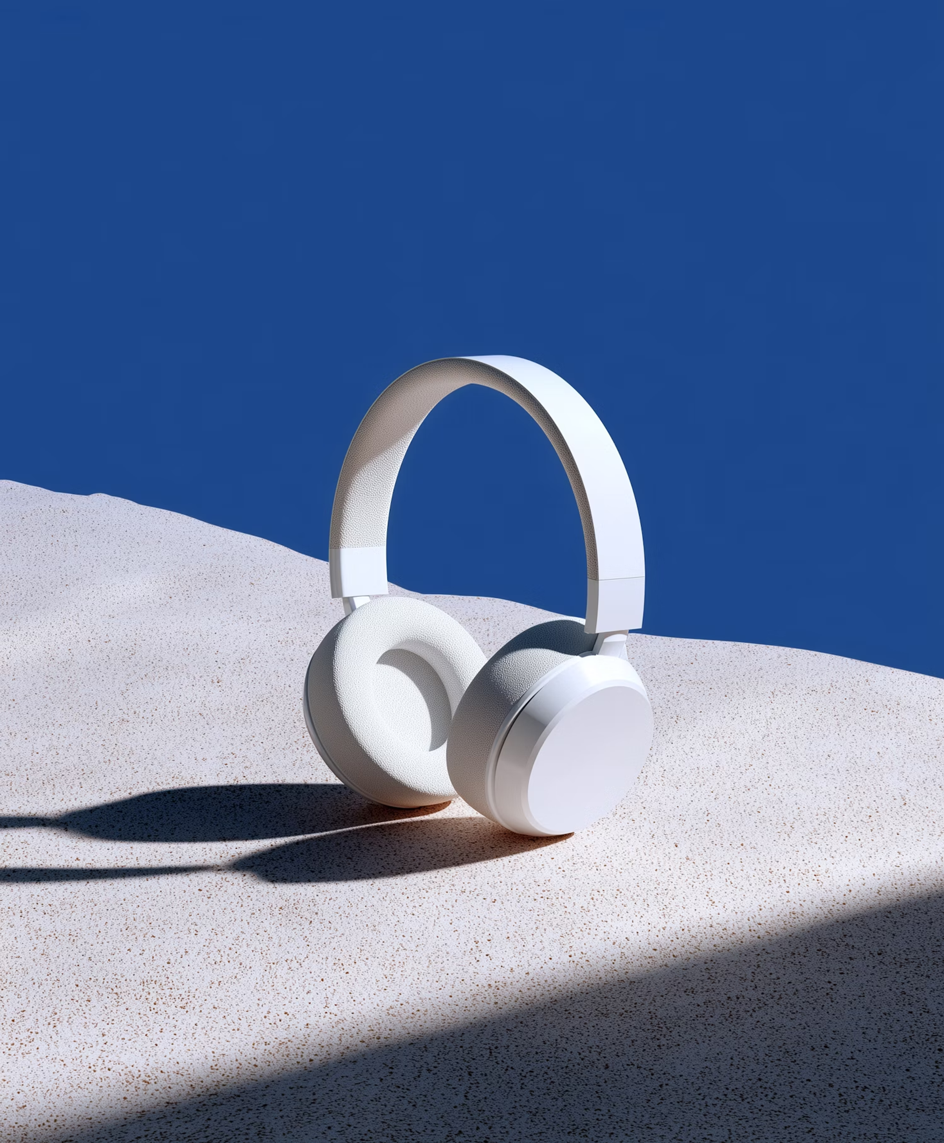 White headphones on sand against a blue wall