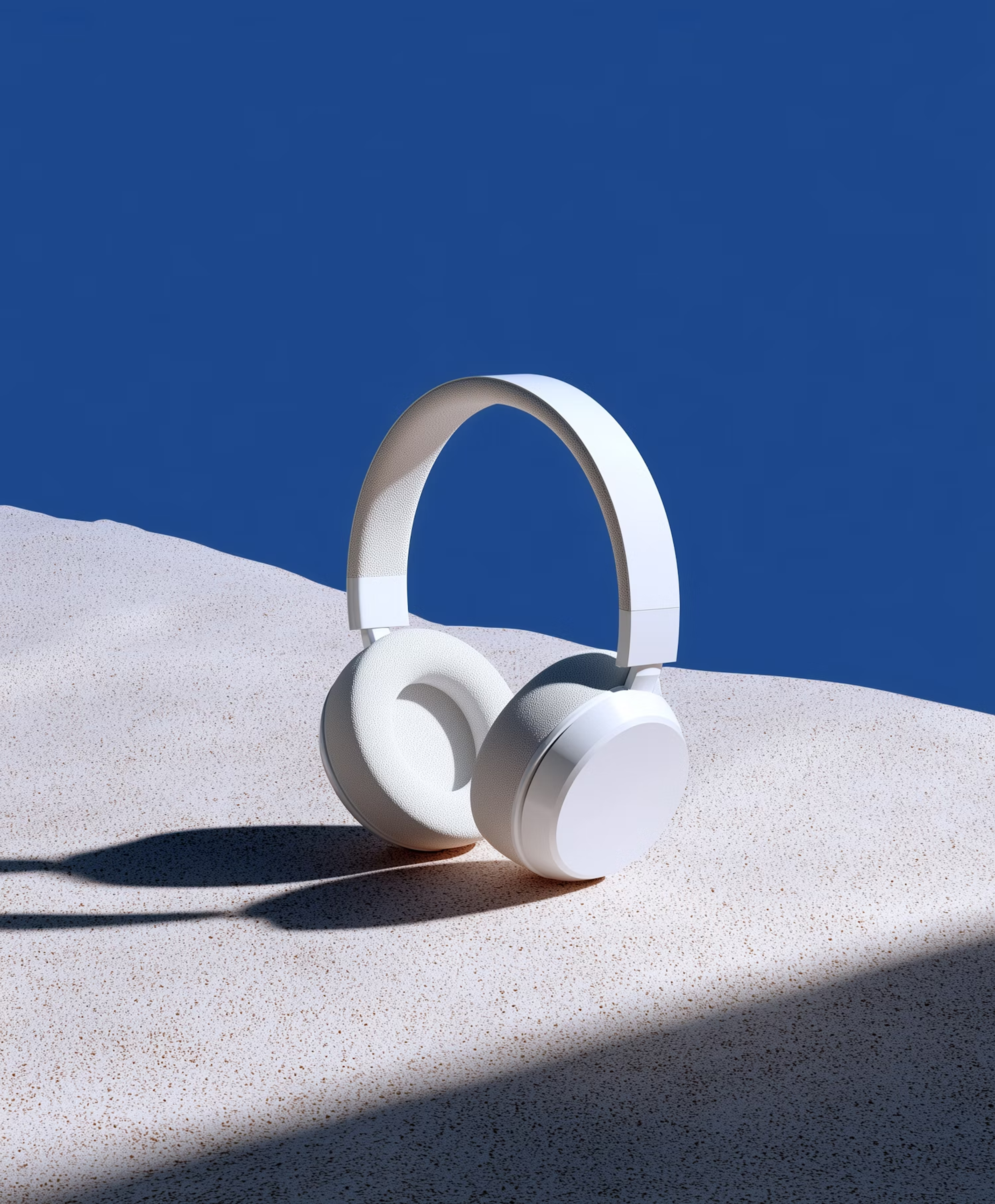 White headphones on sand against a blue wall