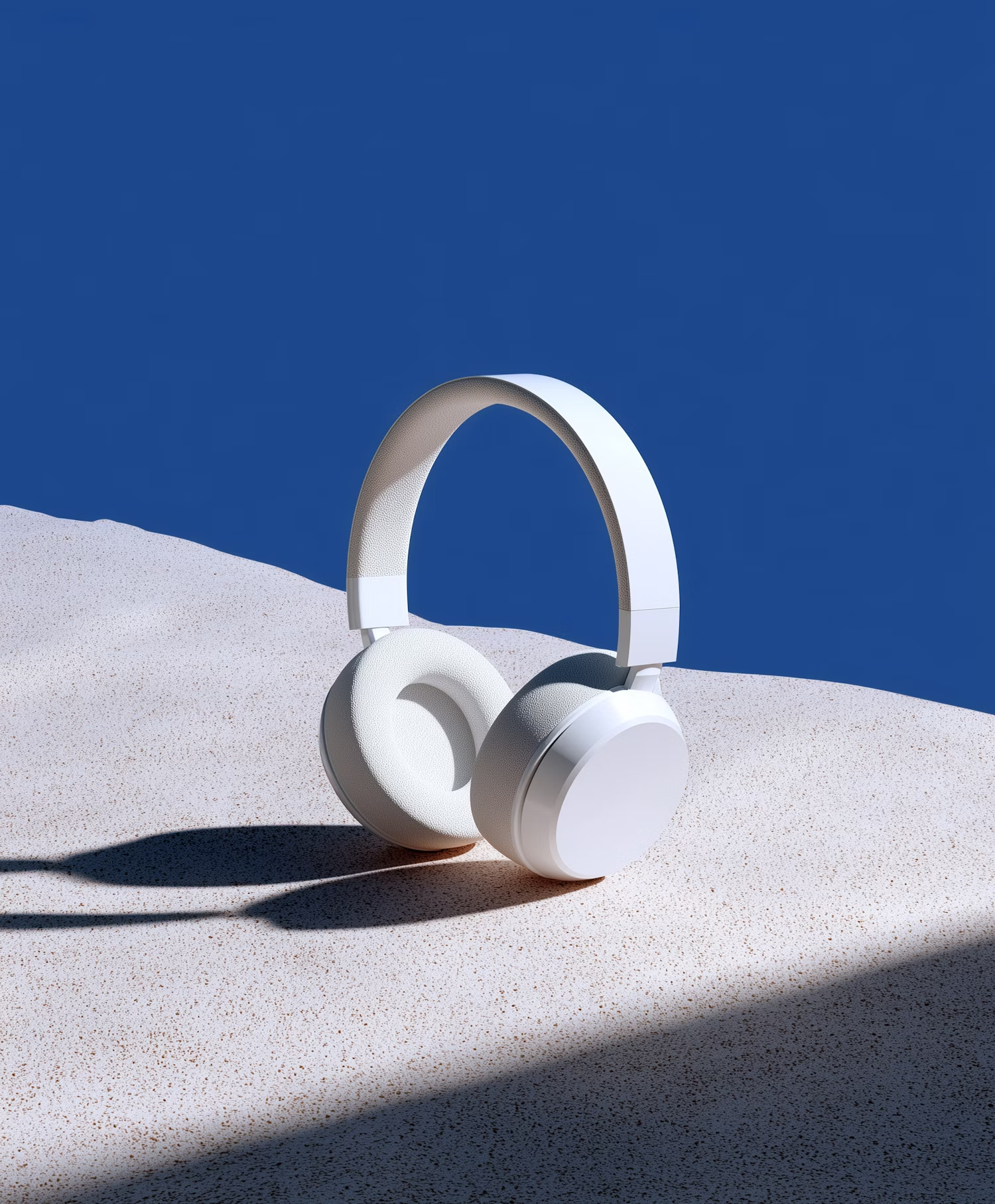 White headphones on sand against a blue wall