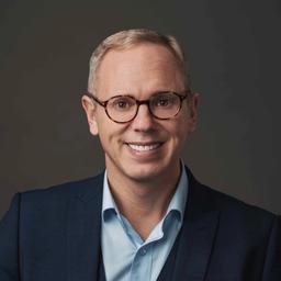 A smiling man wearing glasses and a blue suit.