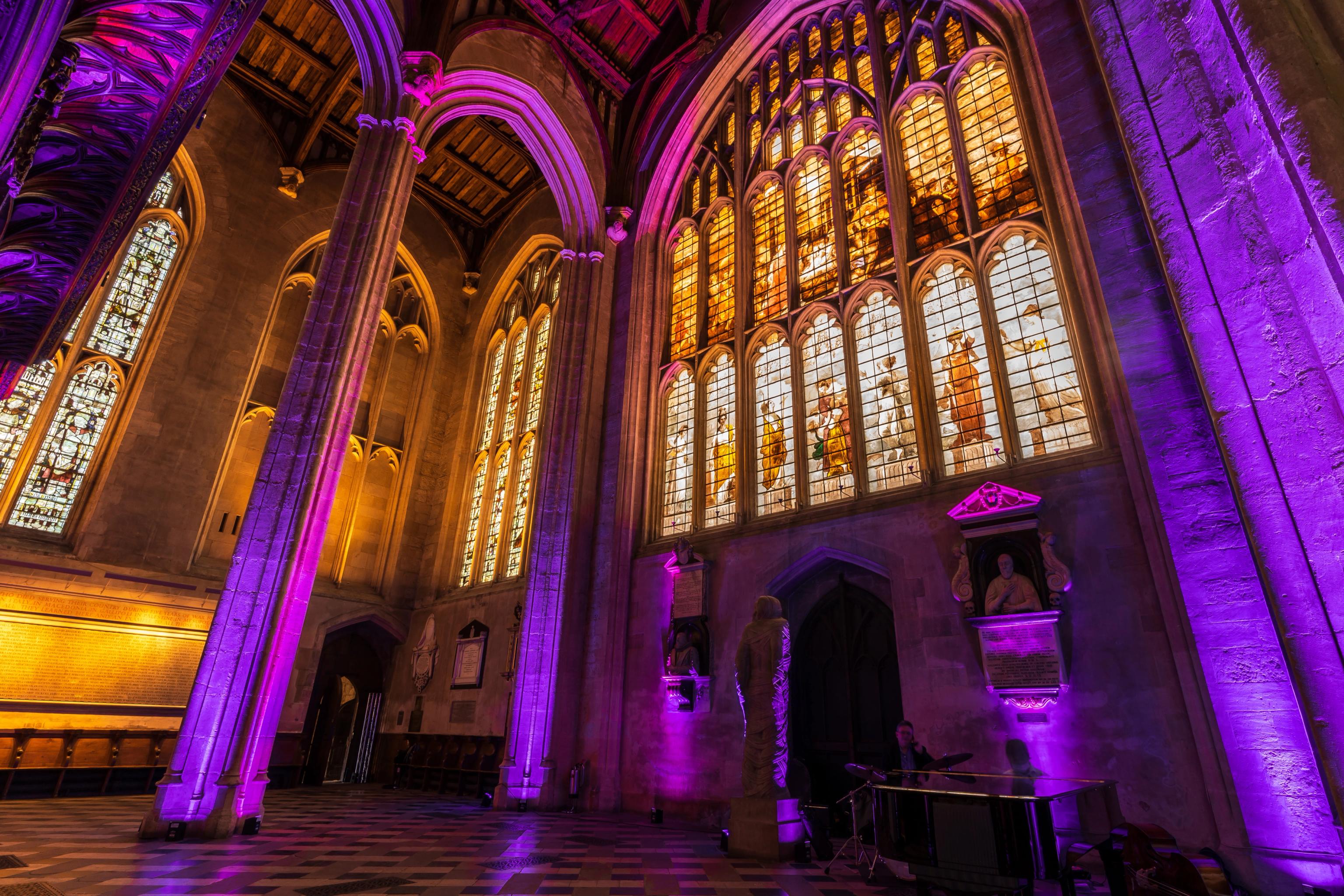 a church with purple lights on the walls and stained glass windows .
