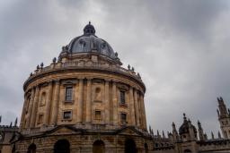 The Radcliffe Camera, a grand circular stone building with a large dome, under a cloudy sky.