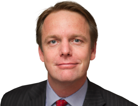 A smiling man with light brown hair wears a pinstripe suit and red tie.