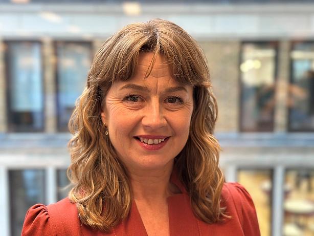 Professional headshot of Sophie White, a woman facing the camera with a neutral background, dressed in smart casual attire and smiling softly.