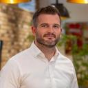 Headshot of a man with a beard and a white shirt smiling.