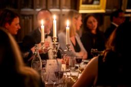 A candlelit dinner with a candelabra on a table surrounded by seated guests.