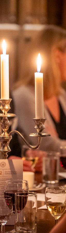 A candlelit dinner with a candelabra on a table surrounded by seated guests.