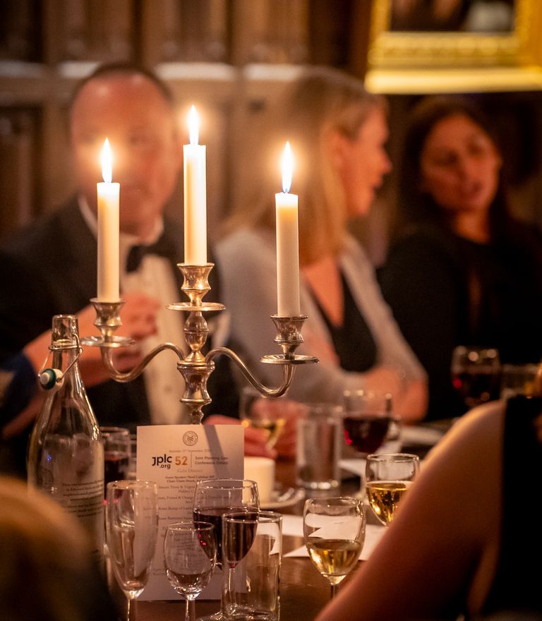 A candlelit dinner with a candelabra on a table surrounded by seated guests.