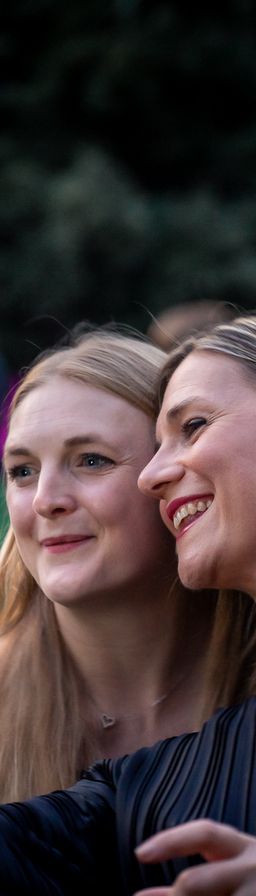 Two smiling women taking a selfie at an outdoor event.