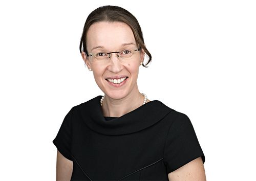 Headshot of a smiling woman with glasses and a pearl necklace.
