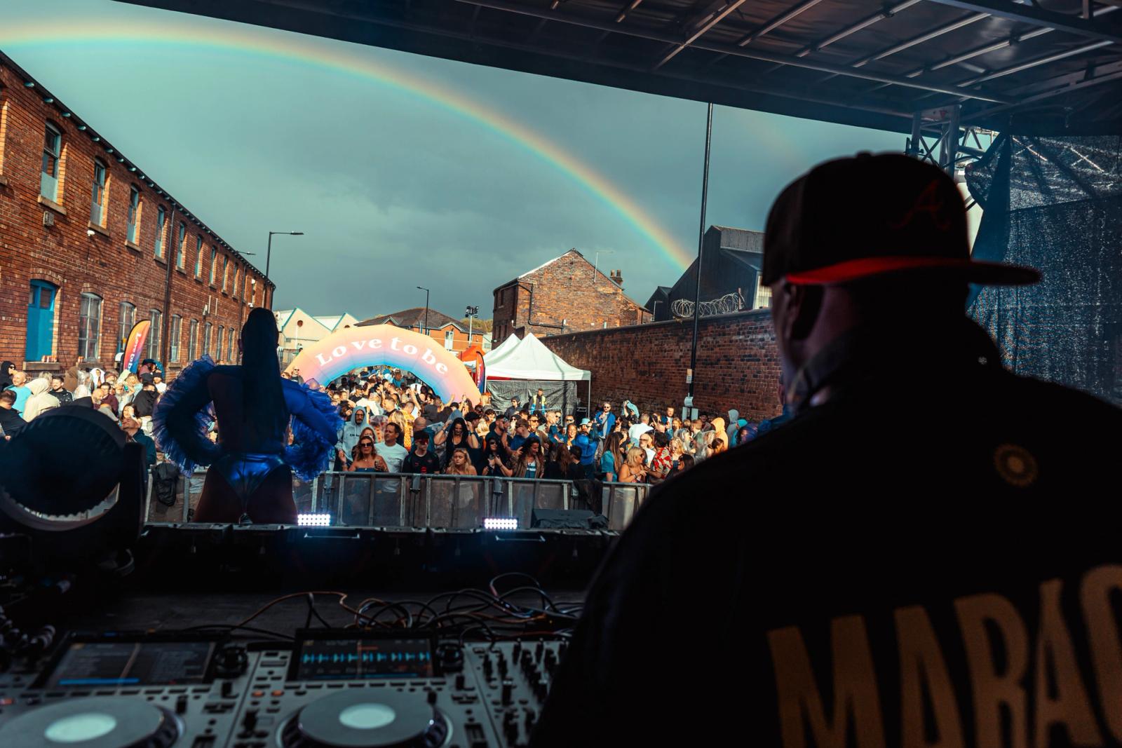 Rainbow over a Northern brick warehouse venue with Love To Be arch