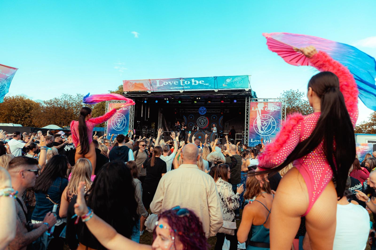 Wide festival shot with Love To Be wordmark stage banner