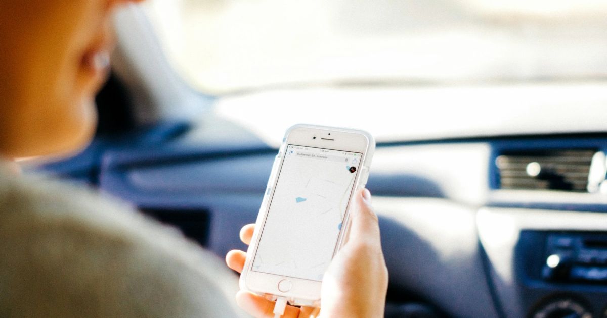 Woman holding an iPhone showing maps in a car