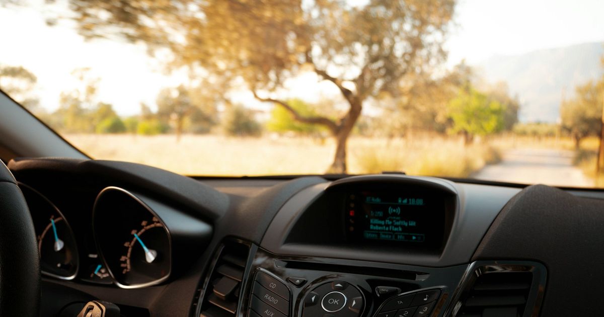 Car dashboard with digital display showing navigation interface in daylight