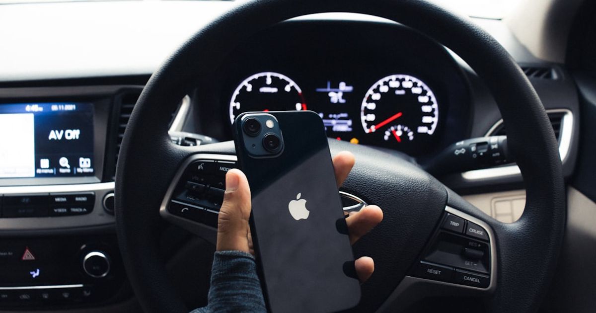 How to Enable CarPlay on iPhone (and Fix It When It Won't Turn On) — a person holding a cell phone in a car