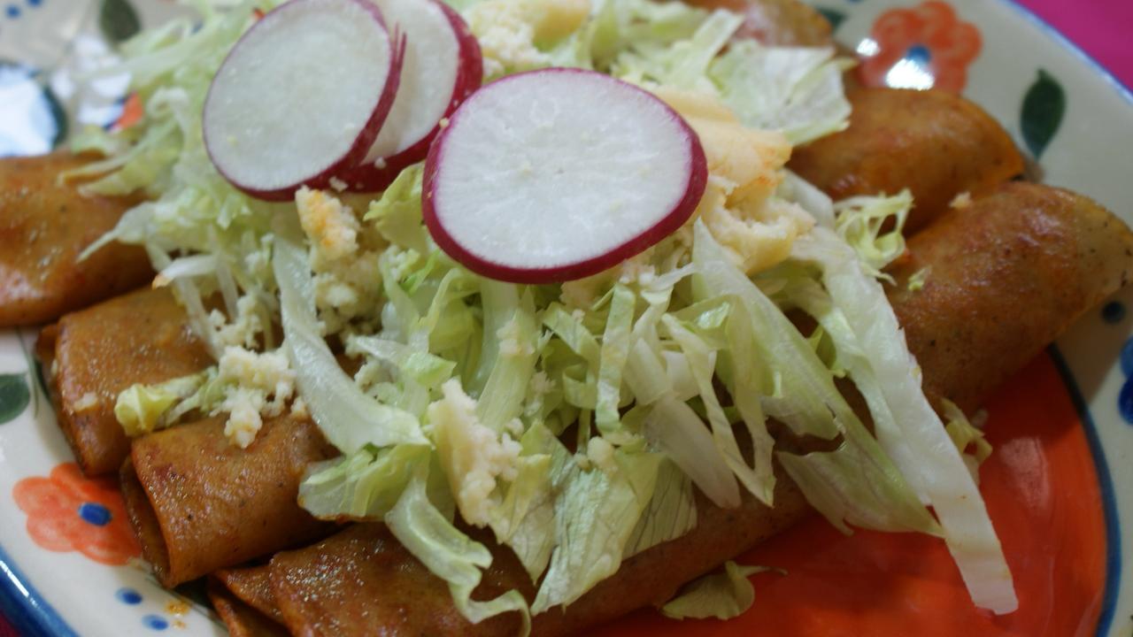 A plate of Mexican enchiladas in red sauce.