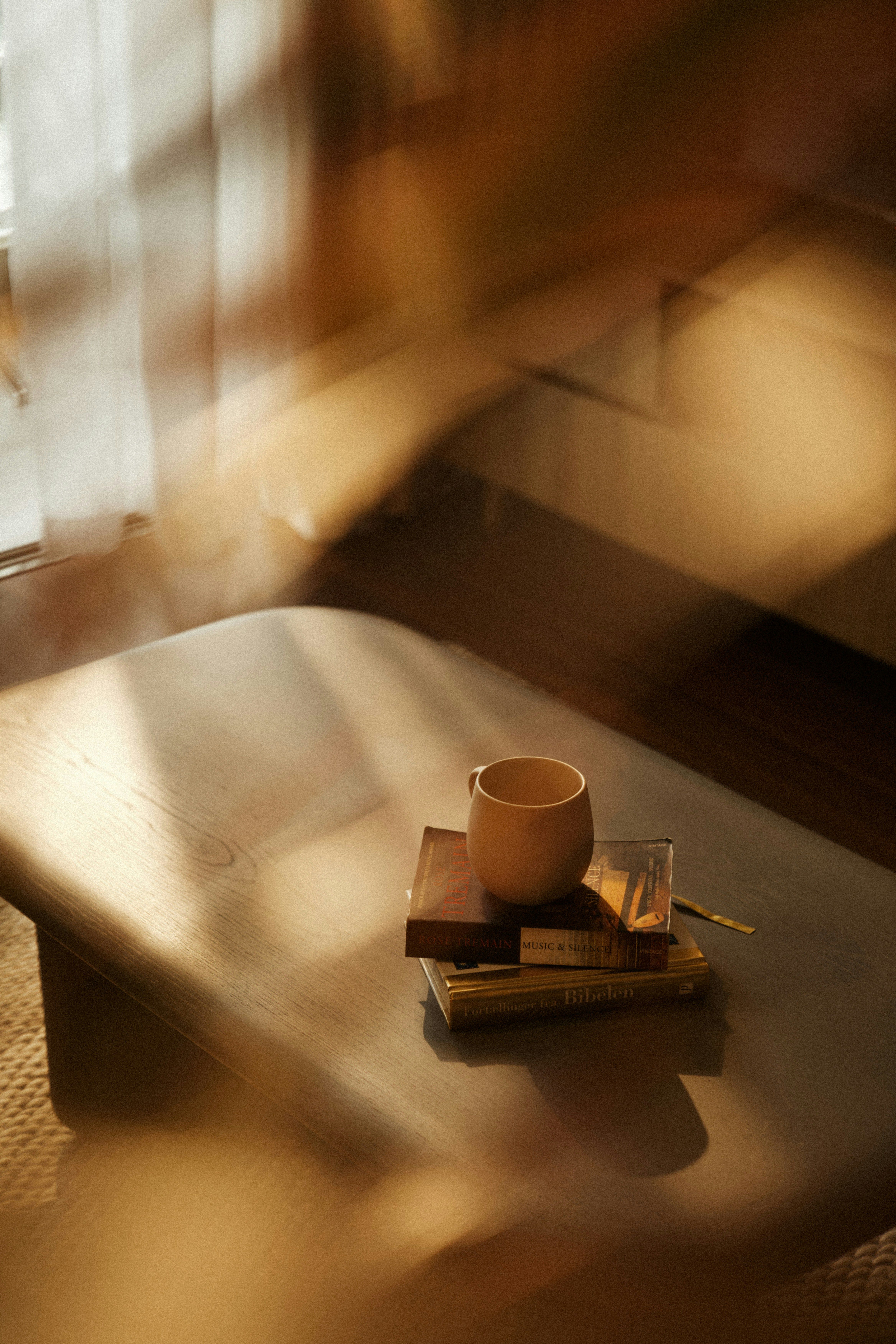 Coffee cup on a stack of books with warm sunlight