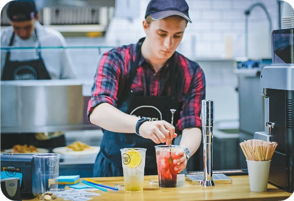 Bartender mixing a red fruit based cocktail.