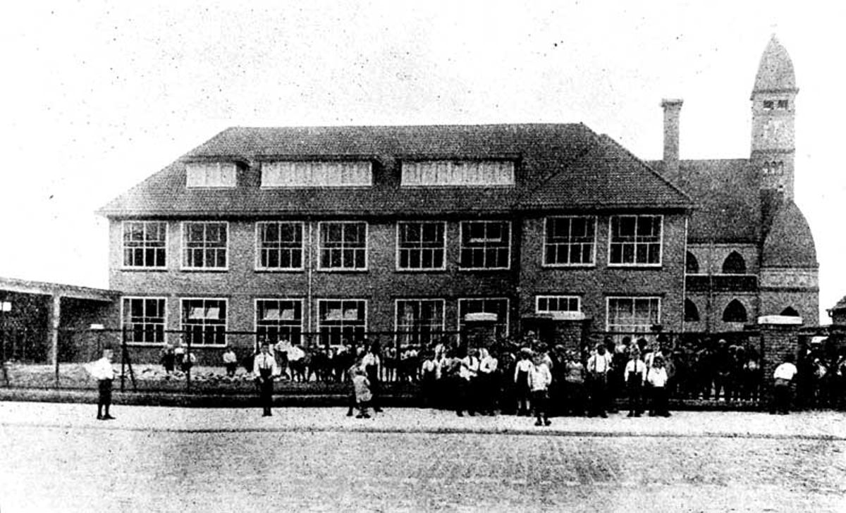 R.K. jongensschool St. Willibrordus met op de achtergrond de St. Theresiakerk, 1930 (foto: Eindhovensche Illustratie. Bron: Regionaal Historisch Centrum Eindhoven, nr. 0026403)