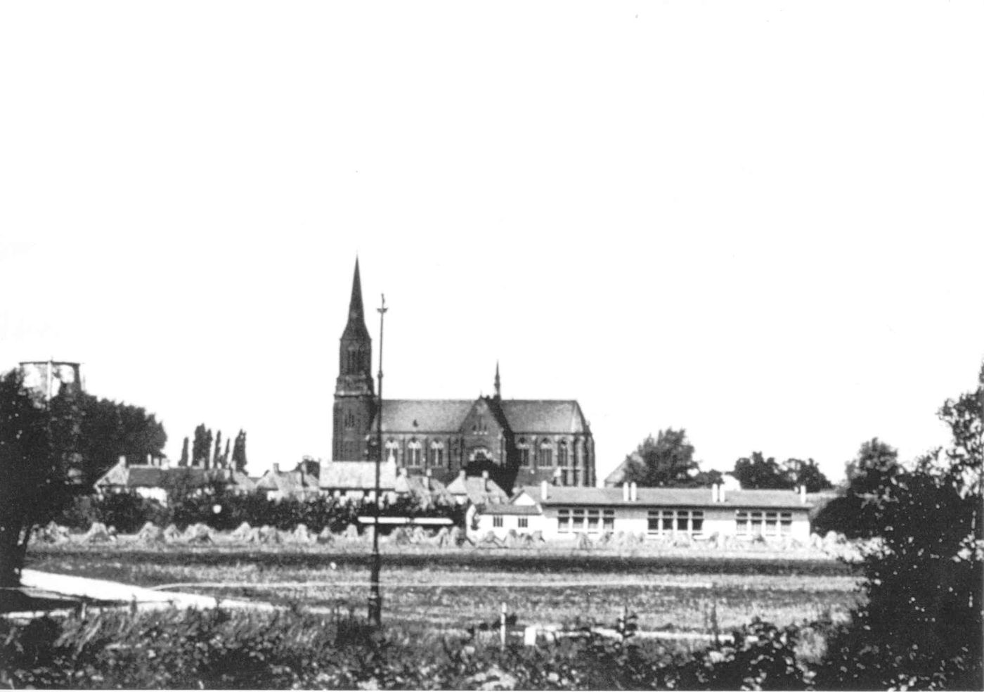 Gezicht op de achterkant van de lagere Landbouwschool achter de molen.
