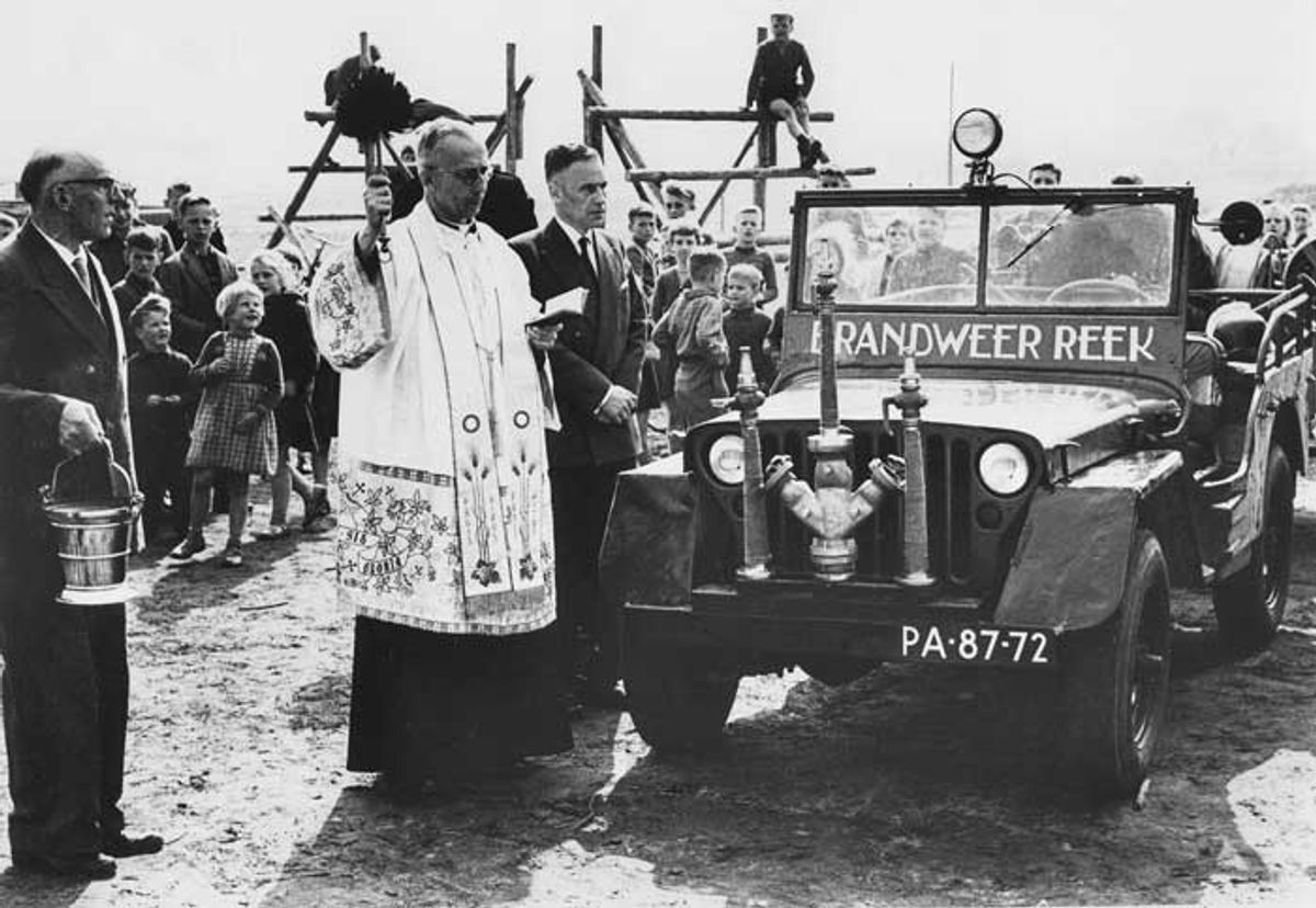 Wijwater voor bluswater. Pastoor Van Berkel uit Schaijk zegent de nieuwe jeep van Brandweer Reek in, onder toeziend oog van burgemeester Van de Ven, 1955. (BHIC, 1903-000405, Beeldcollectie Ton Cruijsen)