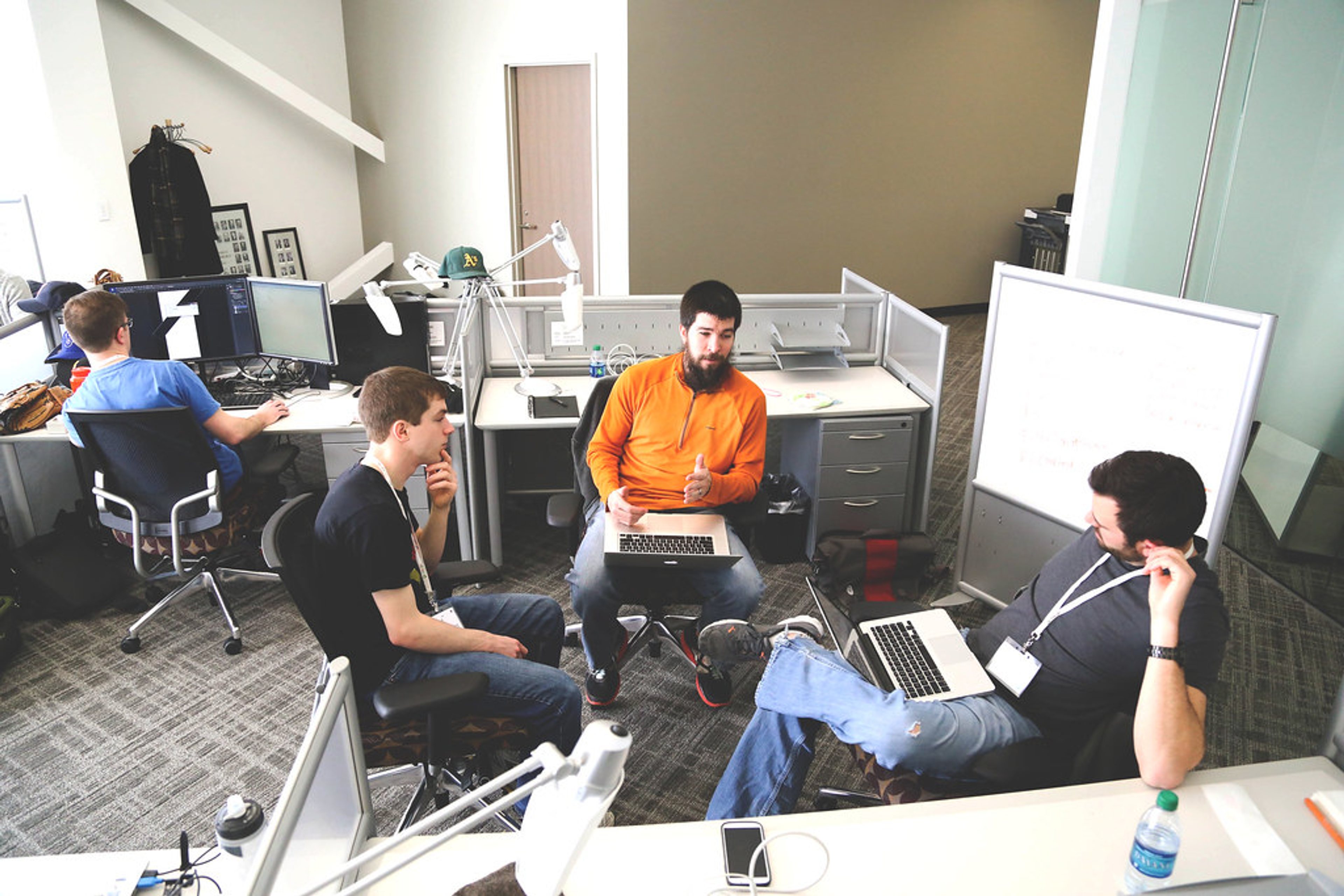 IT professionals discussing workflow intake around laptops in a small business office