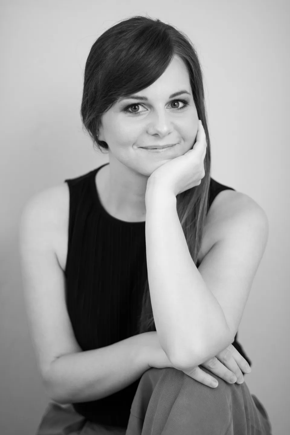 Portrait von Stefanie Kronsteiner, lächelnd, das Kinn auf die Hand gestützt