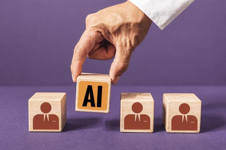 Hand placing an AI block beside three wooden blocks representing people in business roles