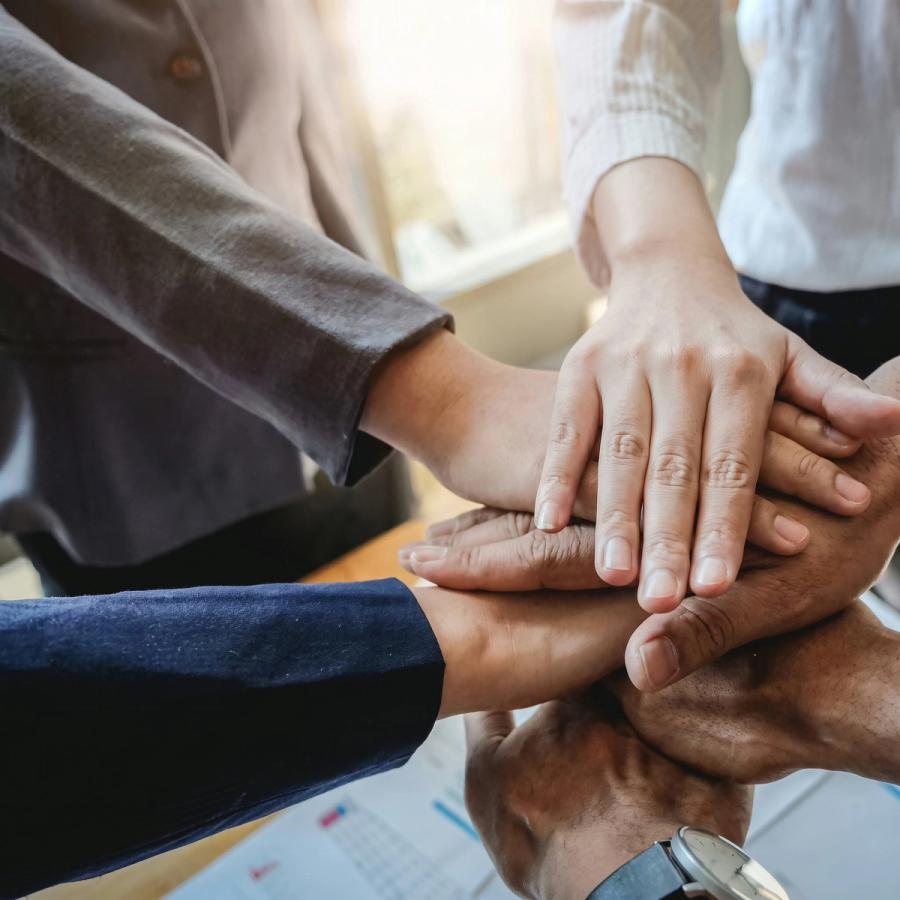 Colleagues bringing their hands together over a desk