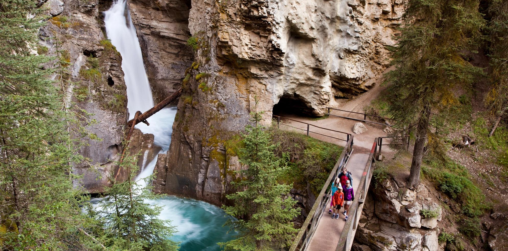 Hikers stand on a catwalk near the lower falls of Johnston's Canyon.