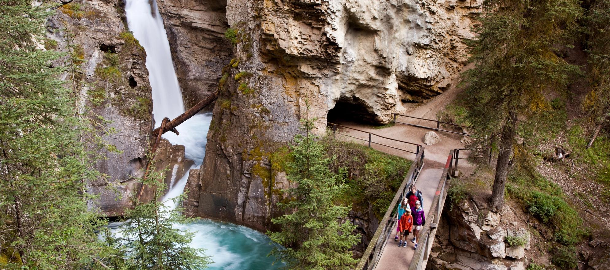 Hikers stand on a catwalk near the lower falls of Johnston's Canyon.