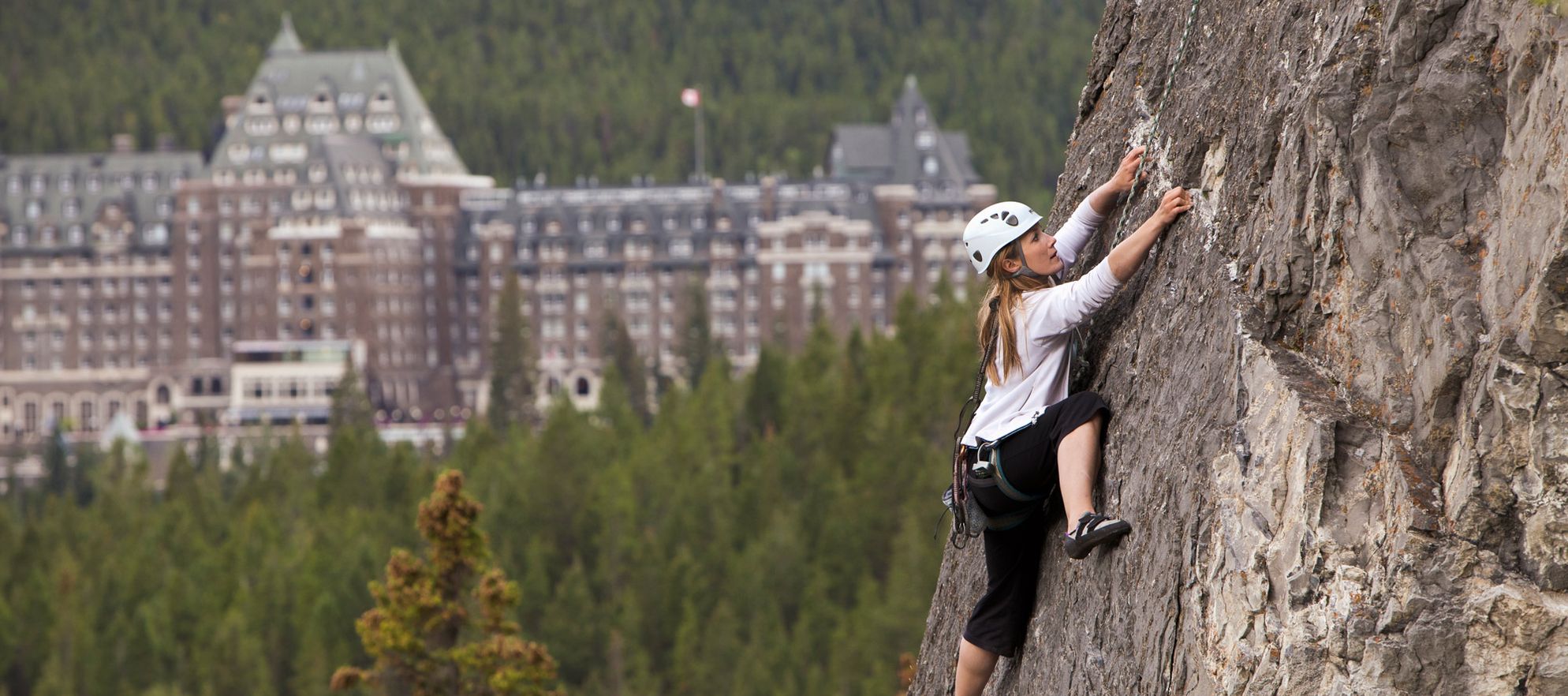 A climber ascends a cliff by the Chateau Lake Louise, Banff National Park, AB