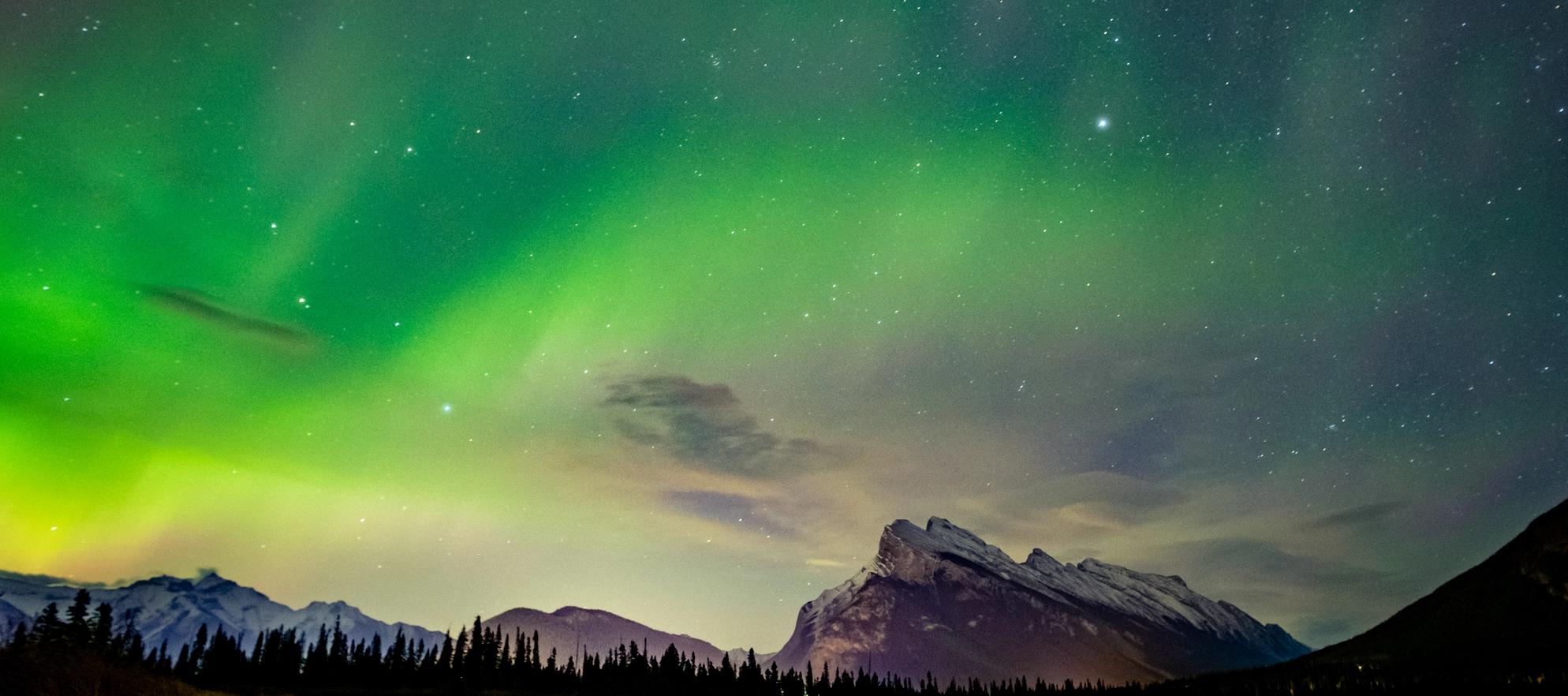 Green aurora and starts glow over Mount Rundle with Vermilion Lakes below