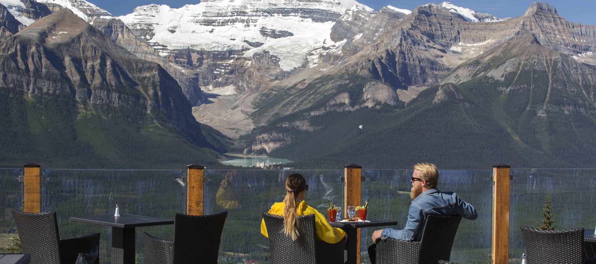 A couple enjoying drinks with a view looking out over Lake Louise from Whitehorn Bistro