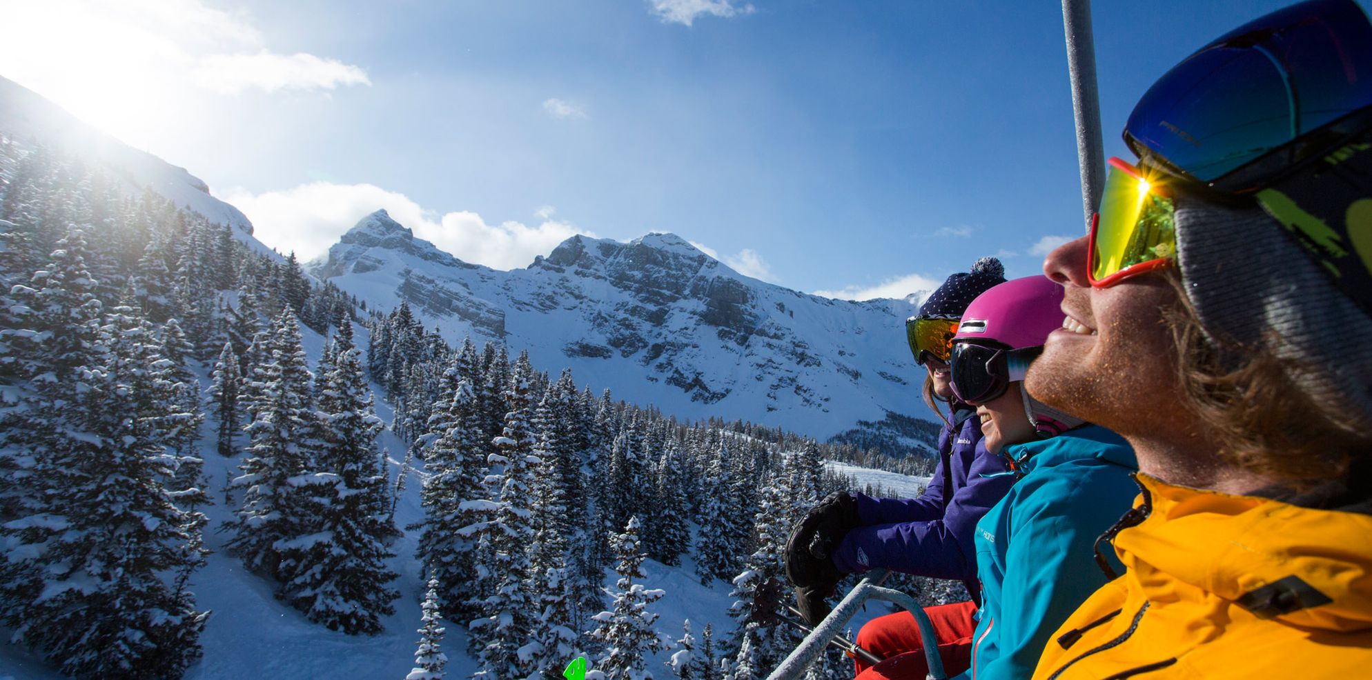 A group of friends soaks in the spring sun while riding the chairlift in Banff National Park, AB