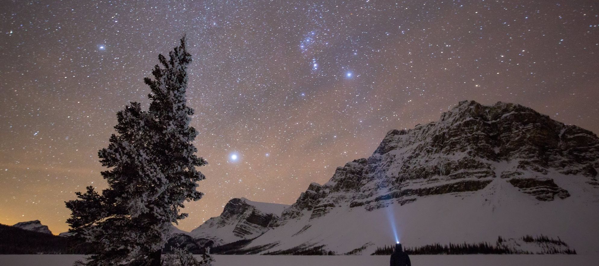 An onlooker takes in the outstandingly clear night skies of Lake Num Ti Jah, just off the Icefields Parkway in Banff National Park, AB.