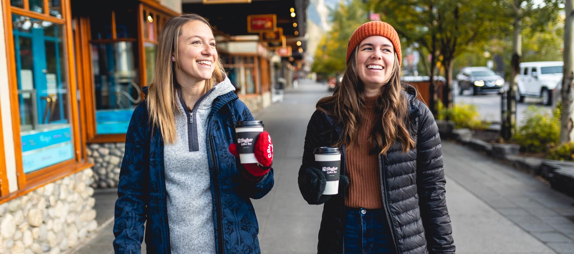 Two women drink coffee on Banff Ave in Banff, Canada.