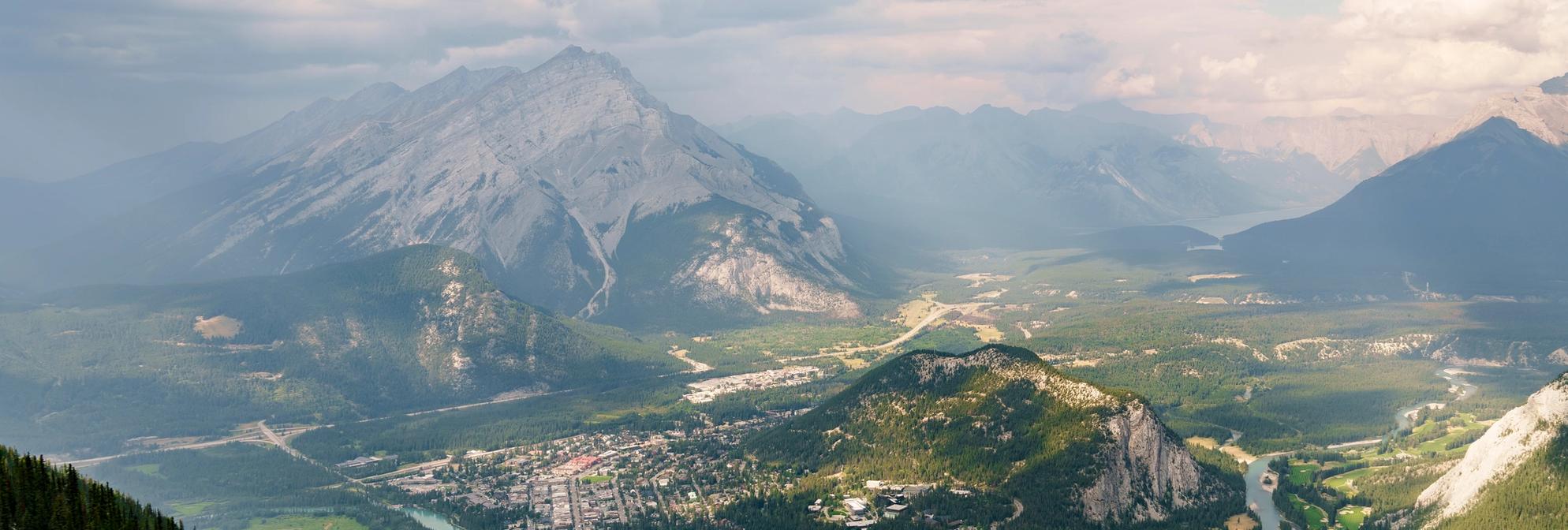 Four people sit in leather chairs at the Banff Centre with mountains in the background while enjoying a glass of wine during an event in Banff National Park.