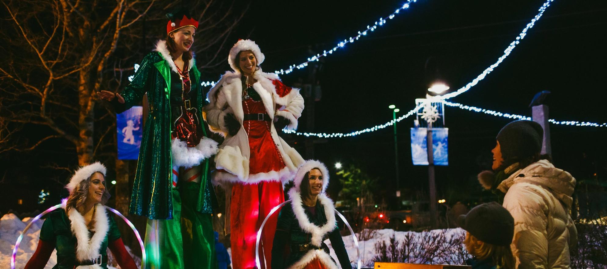 A family watches christmas themed stilt walkers in Banff for the Santa Claus Celebration of Lights