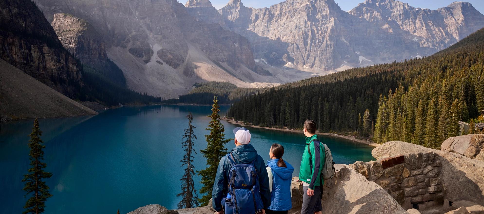 Two people and a tour guide looking out across Moraine Lake from the rockpile viewpoint in Banff National Park.